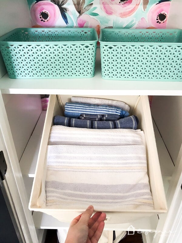 photo of towels stored in canvas bins to help keep linen closet organized