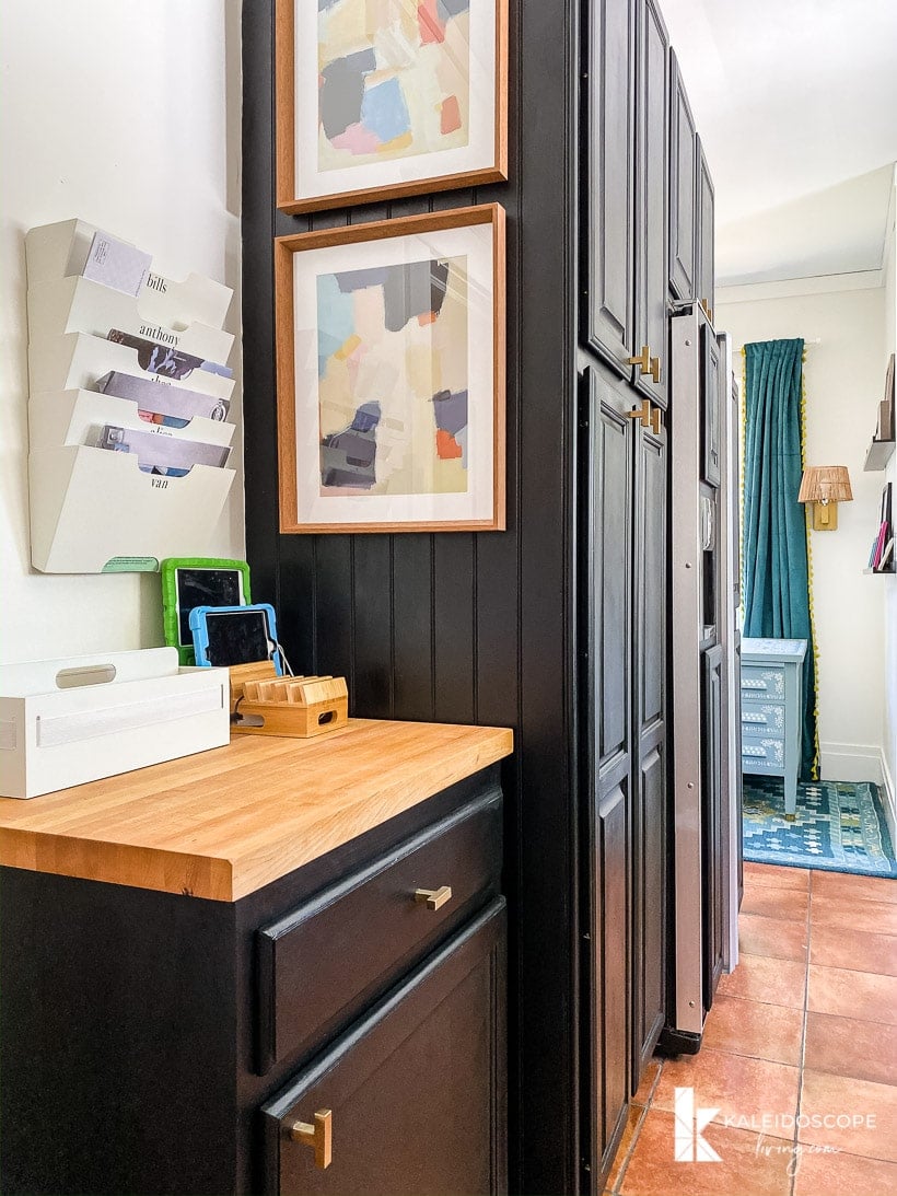 A family "command center" on a small cabinet with a wood top on the other side of a large pantry wardrobe, all added in a budget-friendly kitchen makeover.