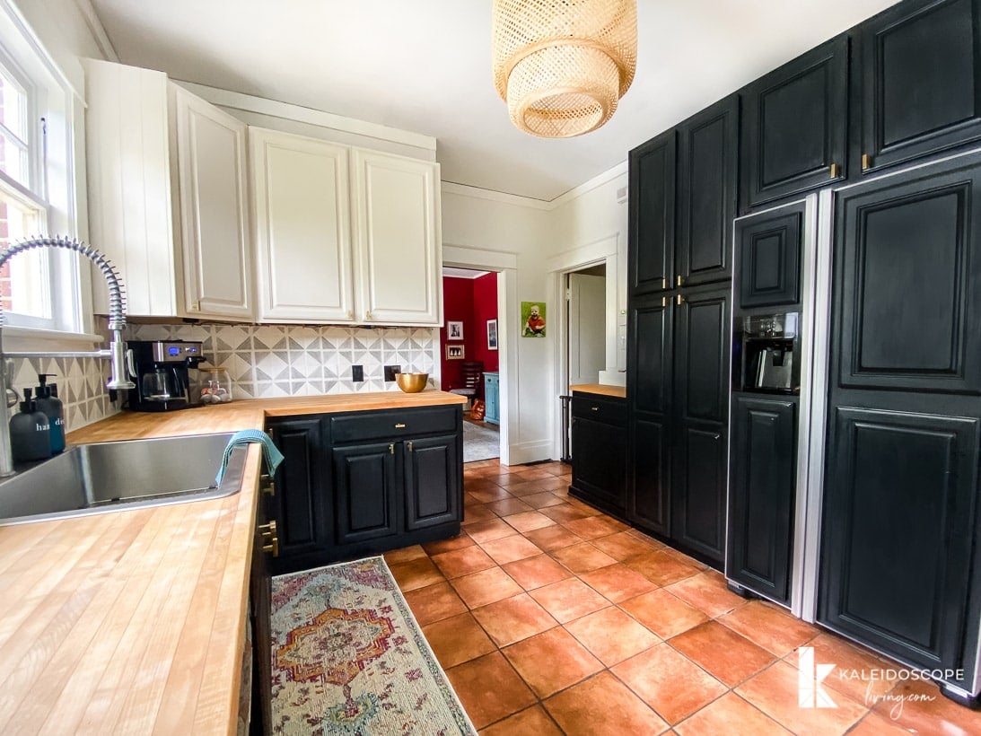 A kitchen remodel for under $1,000 includes painting a wall of cabinets and refrigerator doors black and the upper cabinets white.