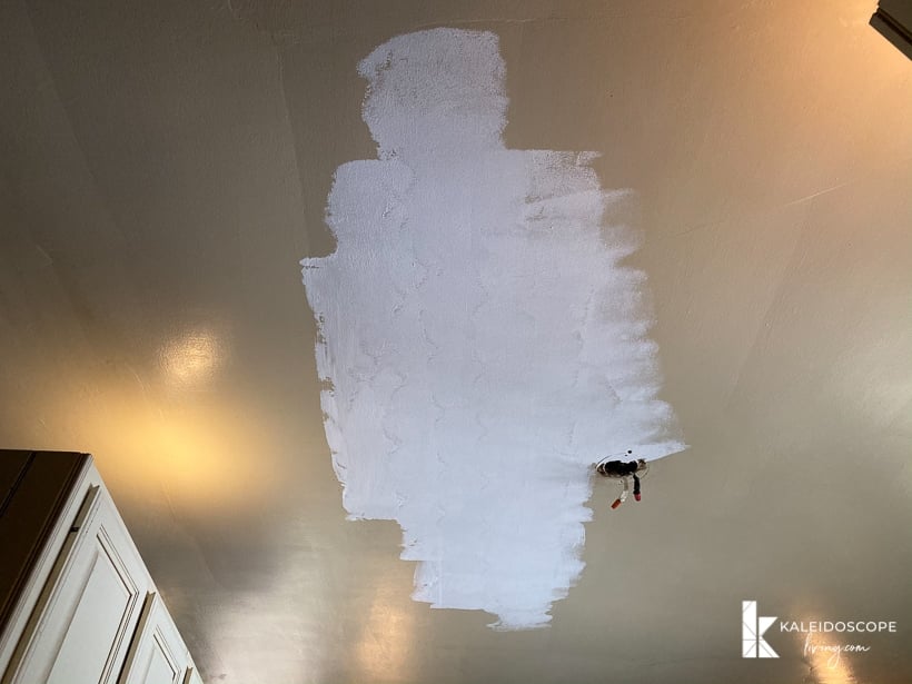 A yellowed kitchen ceiling with an area of white primer is the beginning of a budget-friendly kitchen makeover. The words "KaleidoscopeLiving.com" are in the lower right corner.