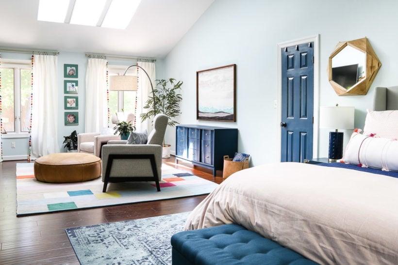 large primary bedroom with area rugs under bed and in sitting area