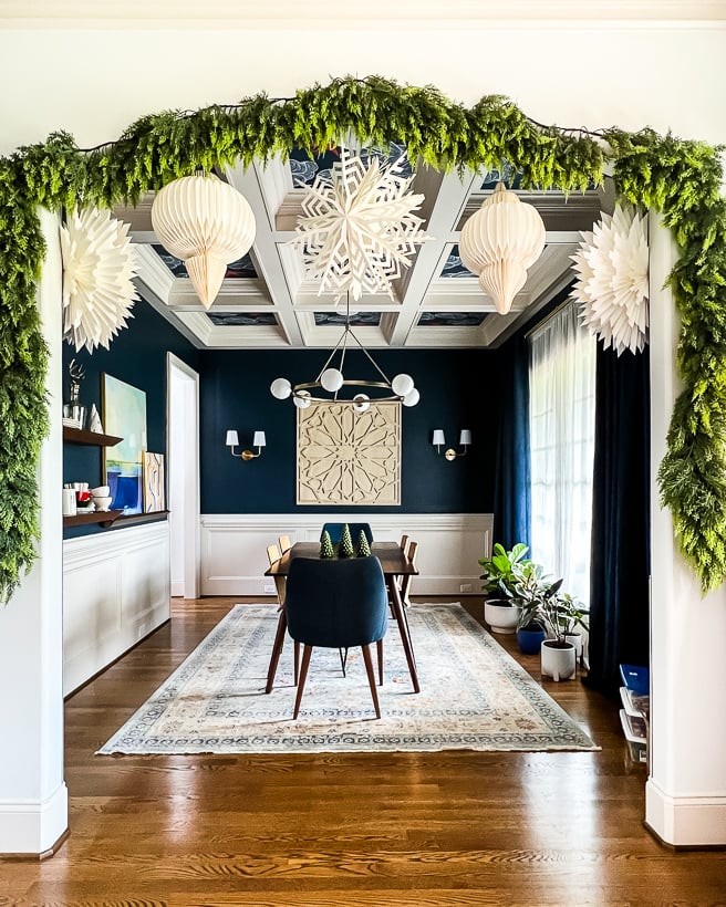 cased opening to dining room decorated with faux garland and paper lanterns