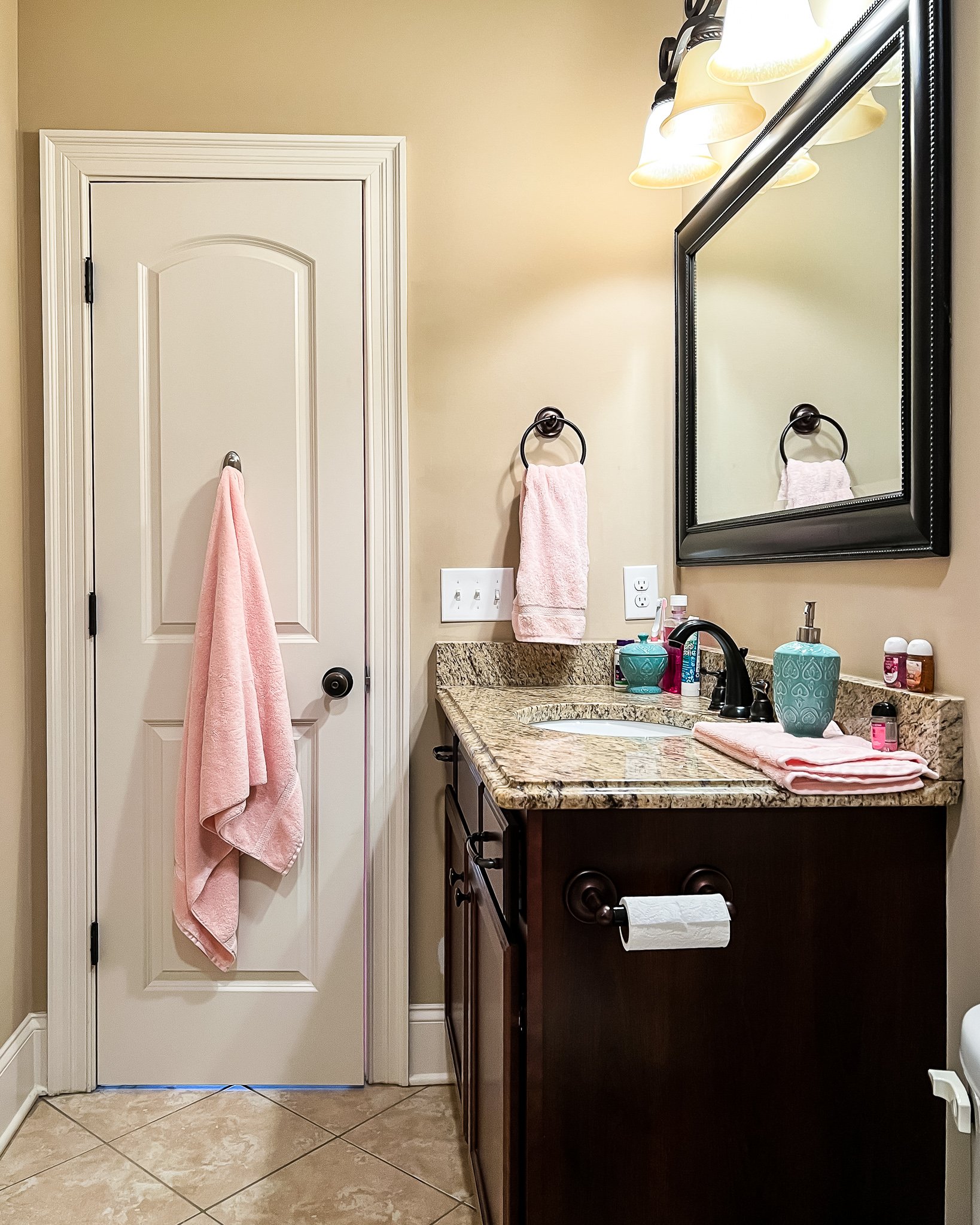 The "before" picture of an outdated bathroom with brown walls and dark wood vanity with beige walls. Paint is essential when doing a bathroom makeover on a budget.