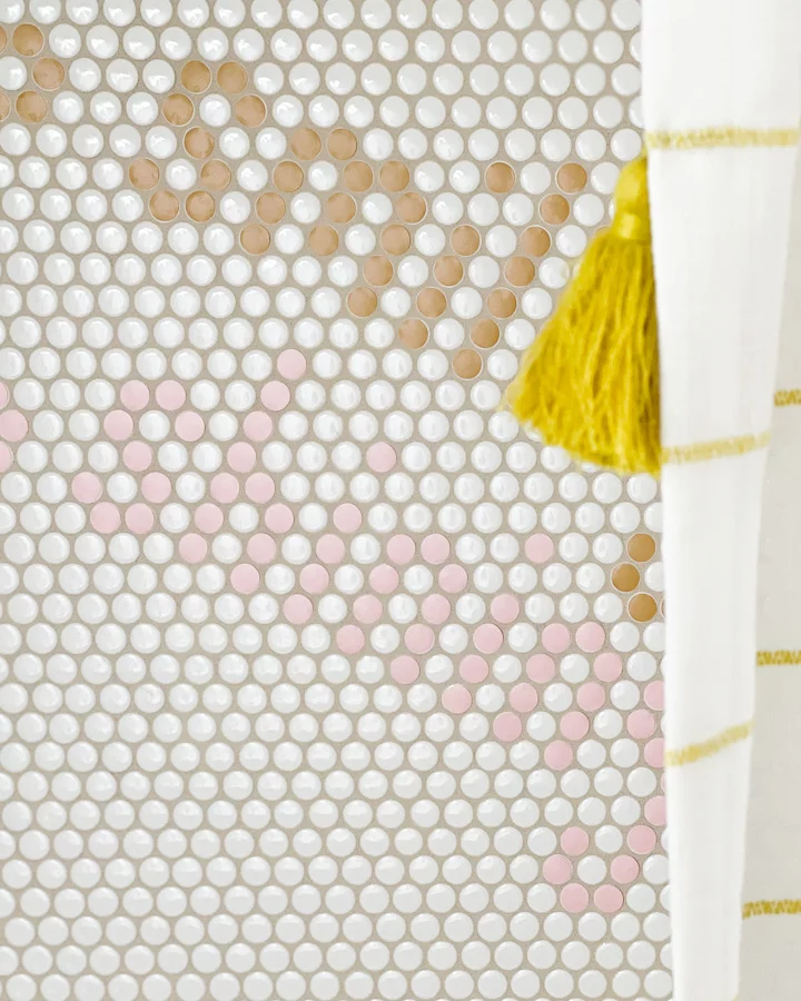 White penny tile in shower has been customized to add the word "smiling" in two different colors.