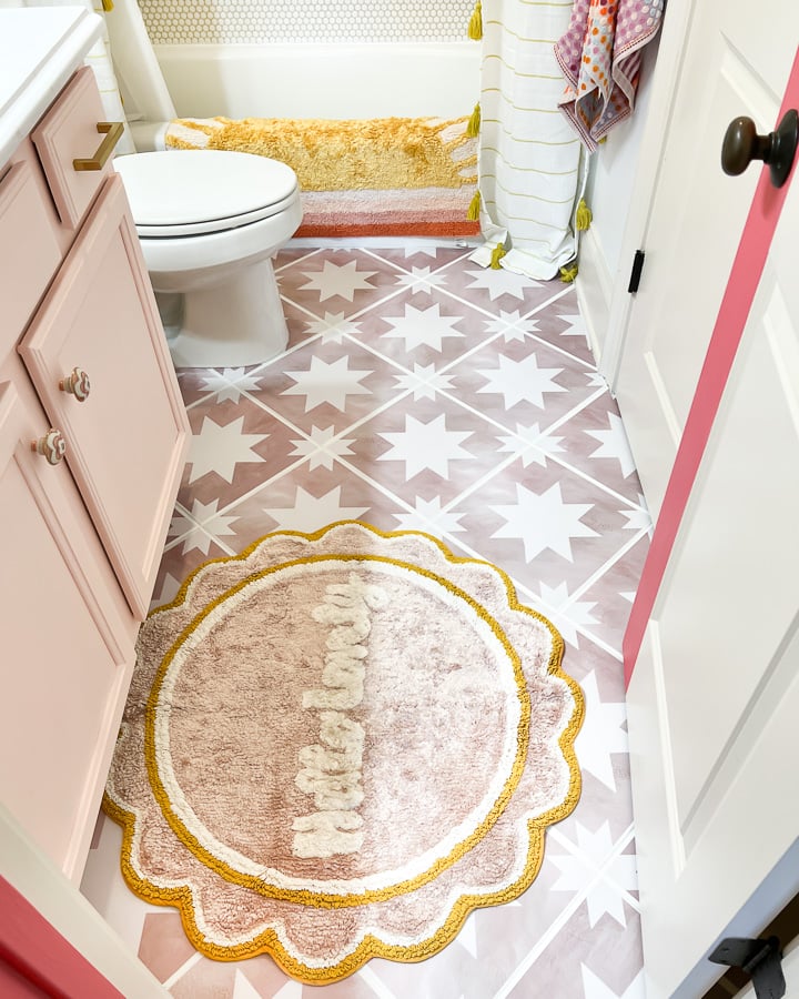 An after photo of a teen girl's bathroom floor updated with pink terracotta tile stickers.