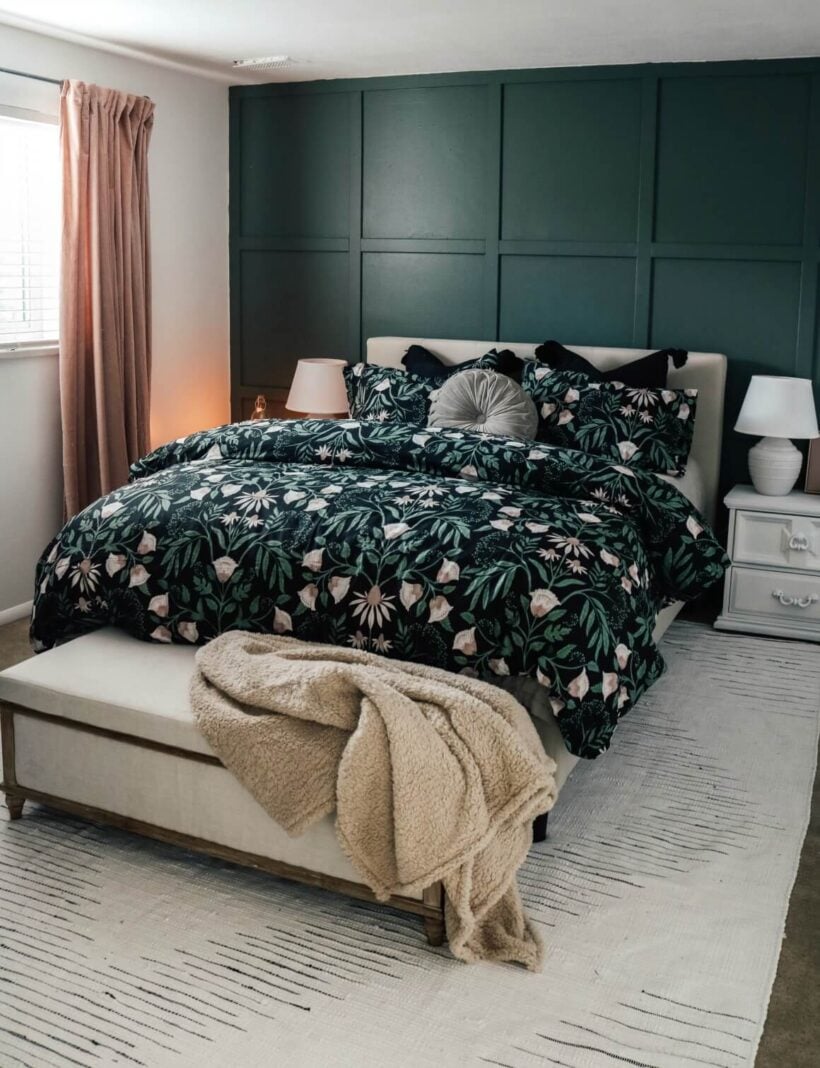 A dark green bedspread stands out against white accents and a deep green board and batten grid pattern on the accent wall.