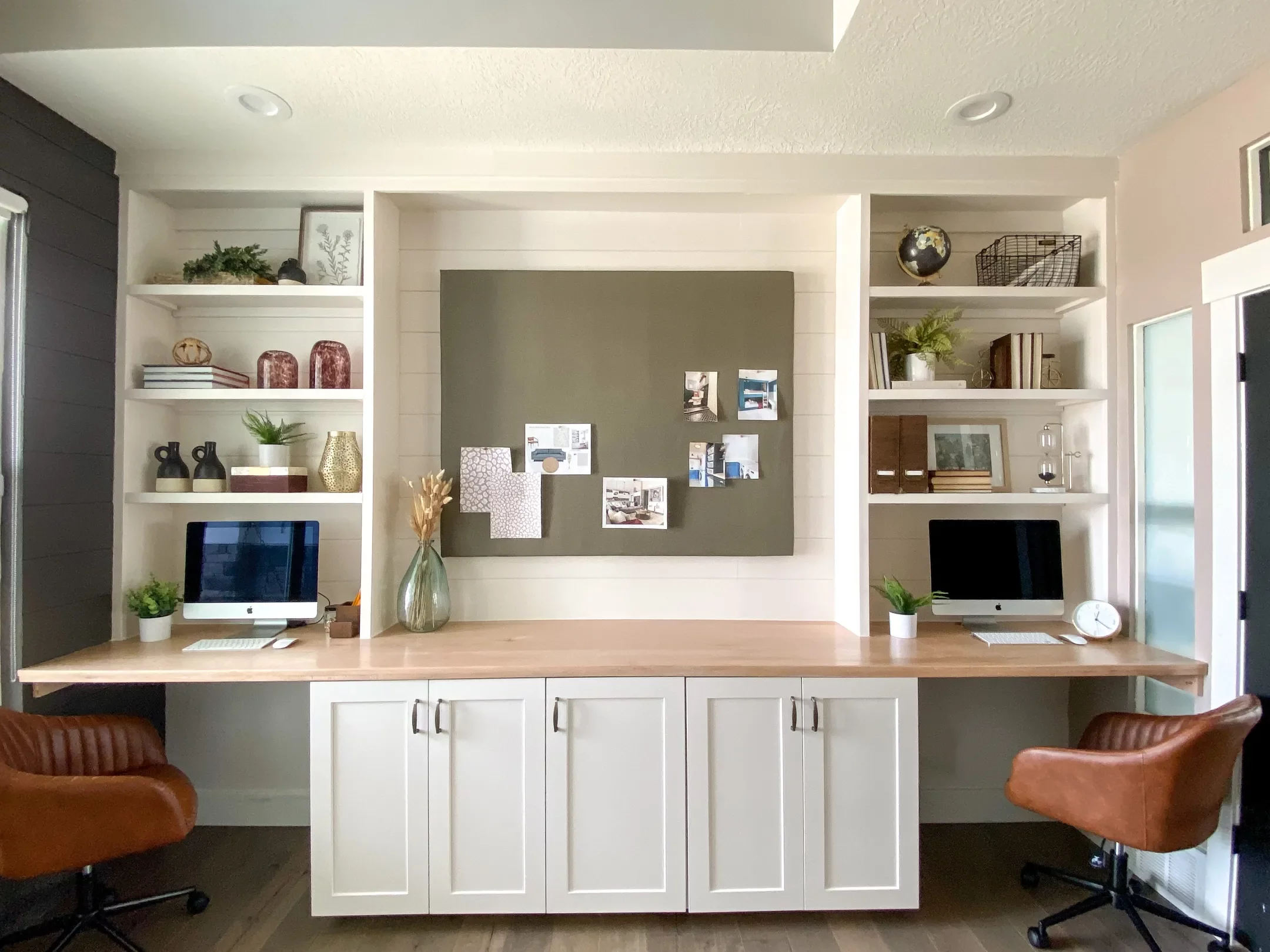 A wood countertop the length of the wall with cabinets underneath and tall bookshelves on either side create a two-person work area from an IKEA desk hack. 