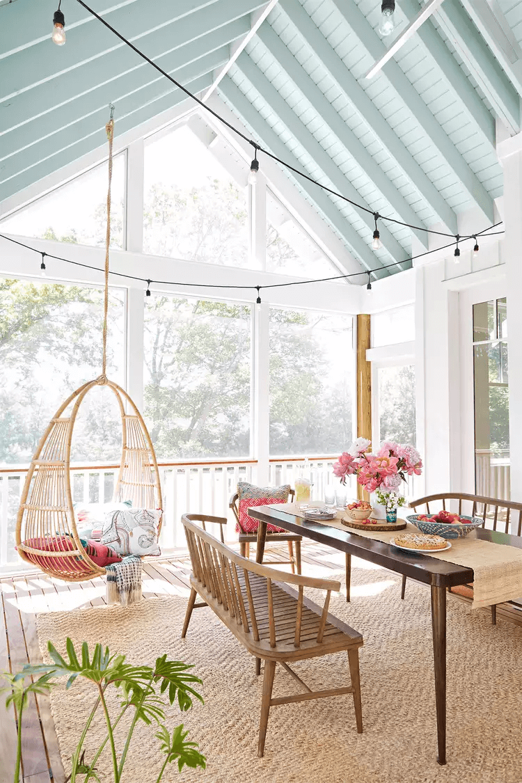 large screened-in porch with metal table and bench seats with blue ceiling