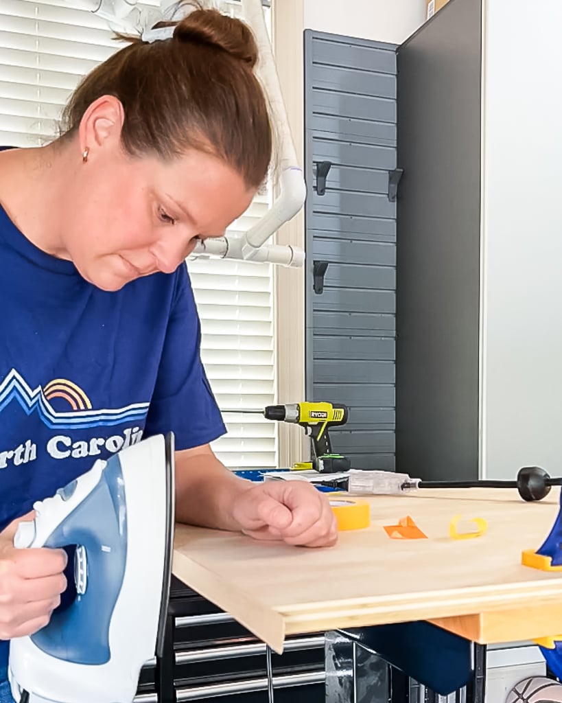 woman ironing edge banding onto edges of plywood