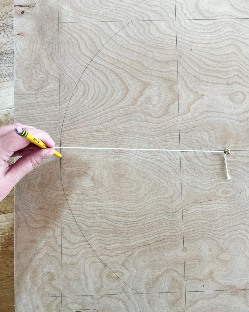 drawing arch shape onto plywood with nail and string attached to pencil