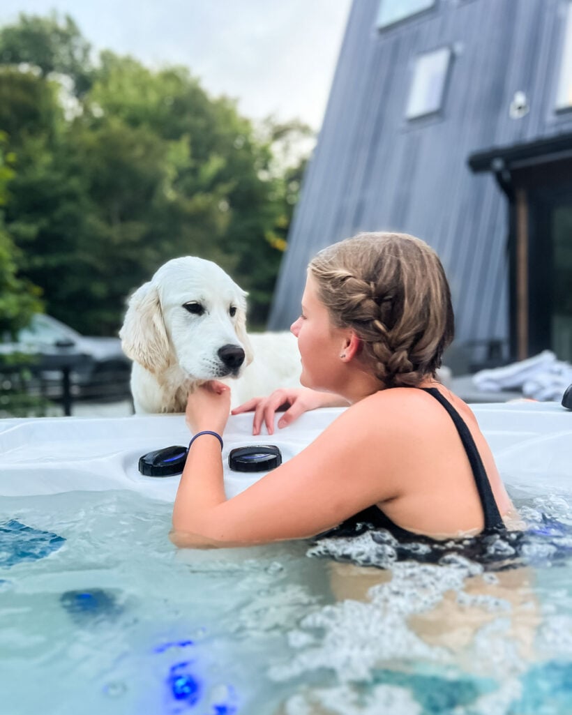 teenage girl in hot tub with English Cream Golden Retriever looking on